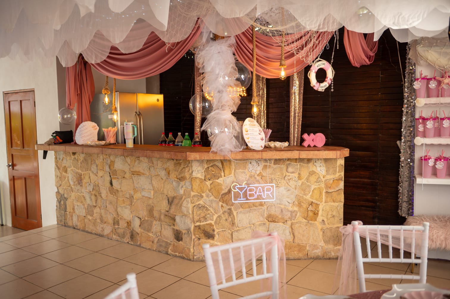 Bar montado con cortinas rosa y copas de bienvenida